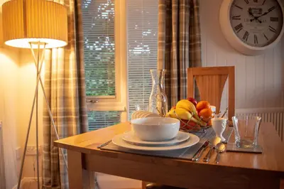 a table with a bowl of fruit and a clock on the wall at Argyll View in Langbank