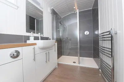 a white bathroom with a shower and a sink at Argyll View in Langbank
