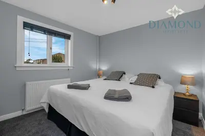 a bedroom with a large white bed with a window at Brand New 4 Bedroom House - Sleeps 4 Fully Equipped, Free Parking, WiFi, Perfect for CONTRACTORS by Diamond Short Lets in Rosyth