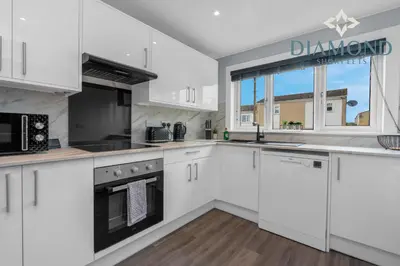 a kitchen with white cabinets and a window at Brand New 4 Bedroom House - Sleeps 4 Fully Equipped, Free Parking, WiFi, Perfect for CONTRACTORS by Diamond Short Lets in Rosyth