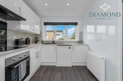 a kitchen with white cabinets and a window at Brand New 4 Bedroom House - Sleeps 4 Fully Equipped, Free Parking, WiFi, Perfect for CONTRACTORS by Diamond Short Lets in Rosyth