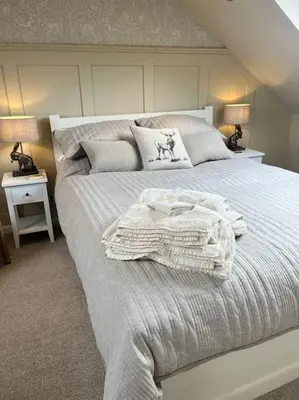 a bedroom with a large white bed with two lamps at Kirkton Rest in Cardross