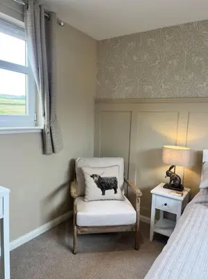 a bedroom with a chair with a cat on a pillow at Kirkton Rest in Cardross