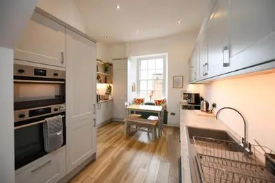 a kitchen with white cabinets and a table in it at Ayrbados - 4 bed townhouse in Ayr in Ayr