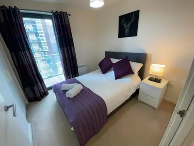 a bedroom with a bed with purple pillows and a window at Glasgow Harbour River West End in Glasgow