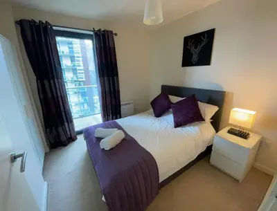 a bedroom with a bed with purple pillows and a window at Glasgow Harbour River West End in Glasgow