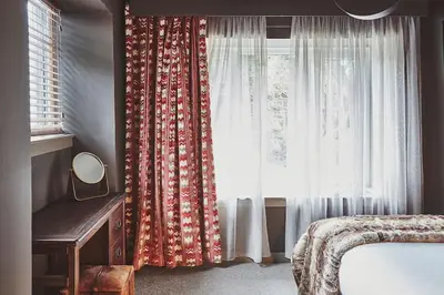a bedroom with a window with curtains and a mirror at Craig Chat in Oban