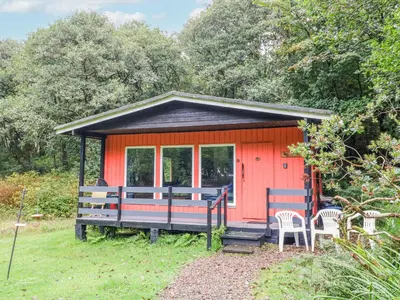a small red cabin with a porch and two chairs at Lodge 1 