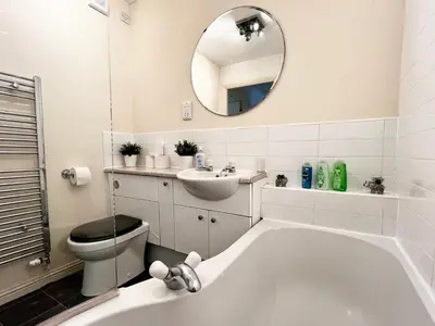 a bathroom with a tub and a toilet and a mirror at Stylish Modern Flat with Juliet Balcony & Parking in Glasgow