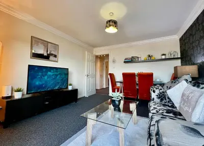 a living room with a couch and a flat screen tv at Stylish Modern Flat with Juliet Balcony & Parking in Glasgow