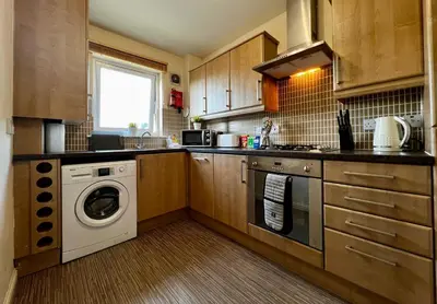 a kitchen with a washing machine and a washer at Stylish Modern Flat with Juliet Balcony & Parking in Glasgow