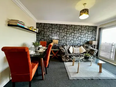 a living room with a table and a couch at Stylish Modern Flat with Juliet Balcony & Parking in Glasgow