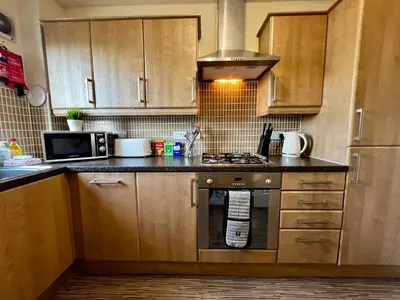 a kitchen with wooden cabinets and a stove top oven at Stylish Modern Flat with Juliet Balcony & Parking in Glasgow