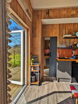 a kitchen with wooden walls and a sliding glass door at Otter Burn Cabin in Oban