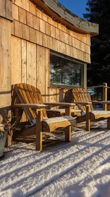 two wooden benches in the snow next to a building at Otter Burn Cabin in Oban