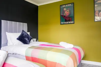 a bedroom with two beds and a yellow wall at Andrew House in Bathgate