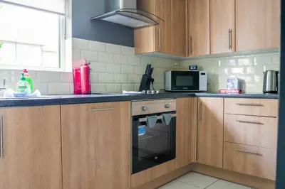 a kitchen with wooden cabinets and a microwave at Andrew House in Bathgate