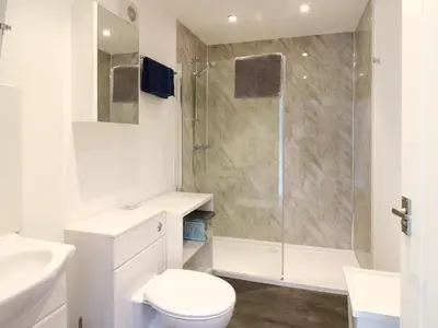 a white bathroom with a shower and a toilet at Tirlaggan House in Oban
