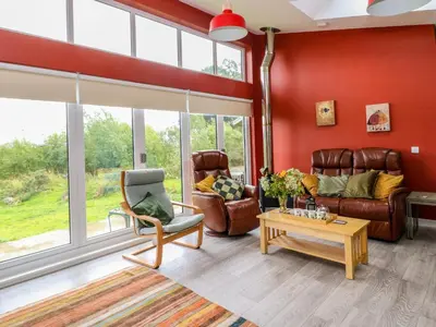a living room with red walls and leather furniture at Tirlaggan House in Oban