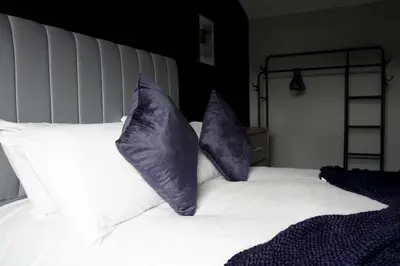 two purple pillows sitting on a white bed at Barclay House in Livingston