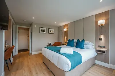 a large bedroom with a large bed with blue pillows at Powfoulis Inn in Falkirk