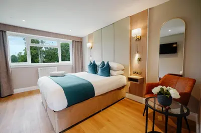 a bedroom with a large bed and a chair at Powfoulis Inn in Falkirk