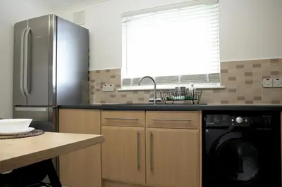 a kitchen with a stainless steel refrigerator and a dishwasher at Sunnyside Penthouse in Coatbridge