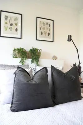 a bedroom with a bed with black pillows and plants at Sunnyside Penthouse in Coatbridge