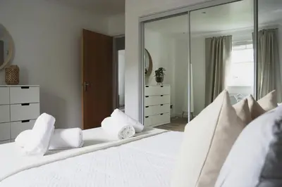 a bedroom with a large white bed with mirrors at Sunnyside Penthouse in Coatbridge