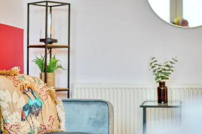 a room with a chair with a pillow and a mirror at Modern 2 Bed Flat with Free Parking in Glasgow