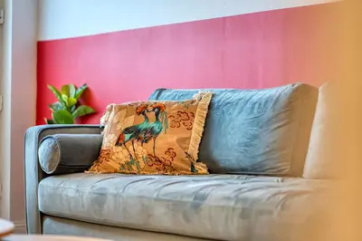 a blue couch with a colorful pillow on it at Modern 2 Bed Flat with Free Parking in Glasgow