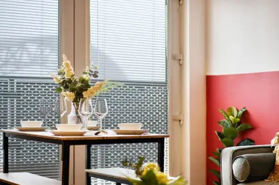 a table with flowers on it in front of a window at Modern 2 Bed Flat with Free Parking in Glasgow