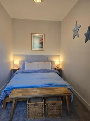 a bedroom with a bed with blue sheets and two stars on the wall at Cumbrae Loft in Millport