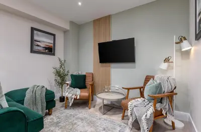 a living room with chairs and a flat screen tv at Central Stirling City Escape in Stirling