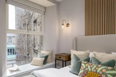 a bedroom with a window and a bed with pillows at Highland Hideaway Apartment in Stirling