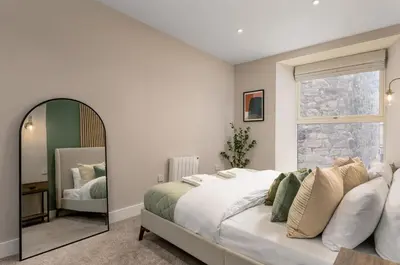 a bedroom with a large bed and a mirror at Highland Hideaway Apartment in Stirling