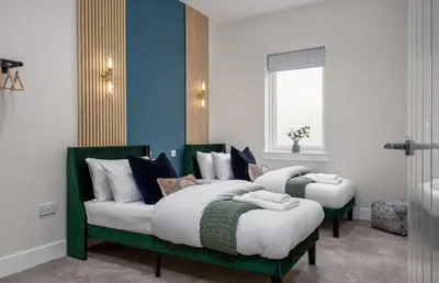 two beds in a room with blue walls at City Centre Haven Apartment in Stirling