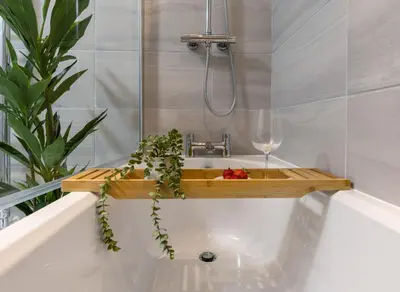 a bath tub with a sink and a glass of wine at City Centre Haven Apartment in Stirling
