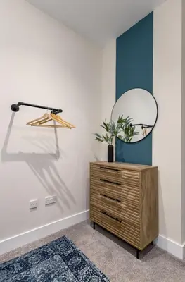 a room with a dresser and a mirror on a wall at City Centre Haven Apartment in Stirling