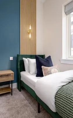 a bedroom with a bed with blue and white pillows at City Centre Haven Apartment in Stirling