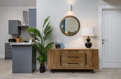 a living room with a wooden dresser and a mirror at City Centre Haven Apartment in Stirling