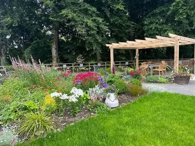 a garden with a wooden pergola and a bunch of flowers at Modern Accessible Apartment with Interconnecting Room in Dolphinton