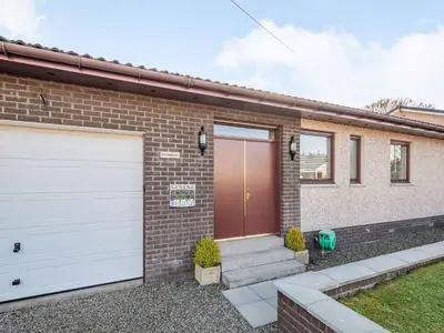 a brick house with two white garage doors at Mousebank in Lanark