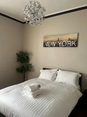 a bedroom with a bed with white sheets and a chandelier at One Bedroom Apartment in Gorgie with new central heating system in Edinburgh