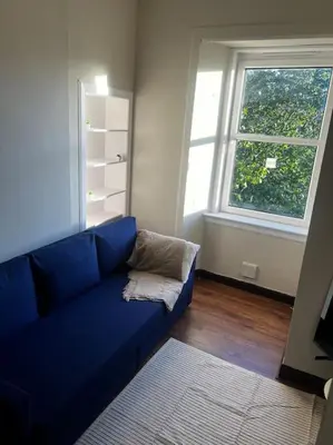 a blue couch in a living room with a window at One Bedroom Apartment in Gorgie with new central heating system in Edinburgh