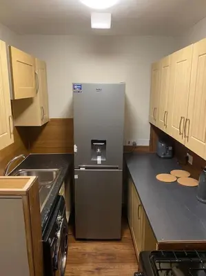 a kitchen with a stainless steel refrigerator and wooden cabinets at One Bedroom Apartment in Gorgie with new central heating system in Edinburgh