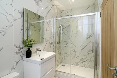 a bathroom with a shower and a sink and a mirror at The Manor - Beachwalk Apartments in Ayr