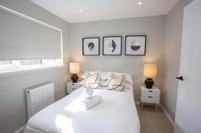 a bedroom with a white bed with two lamps at Stylish and Modern 2 Bed House in Glasgow