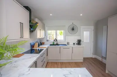 a white kitchen with white cabinets and a window at Stylish and Modern 2 Bed House in Glasgow
