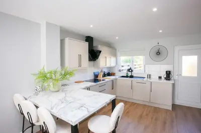 a white kitchen with a table and chairs at Stylish and Modern 2 Bed House in Glasgow